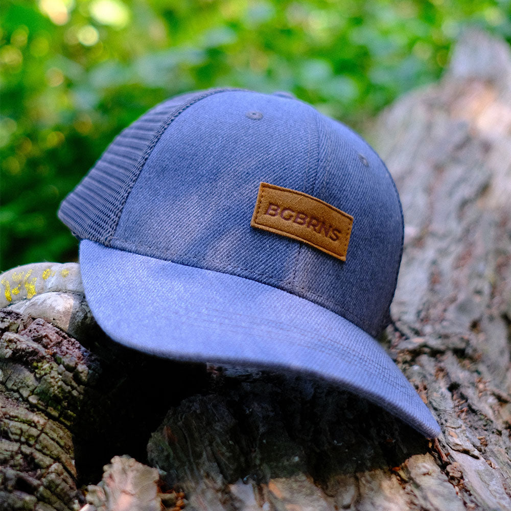 Die XXL Trucker Cap von BigBrains liegt auf einem Baumstamm.