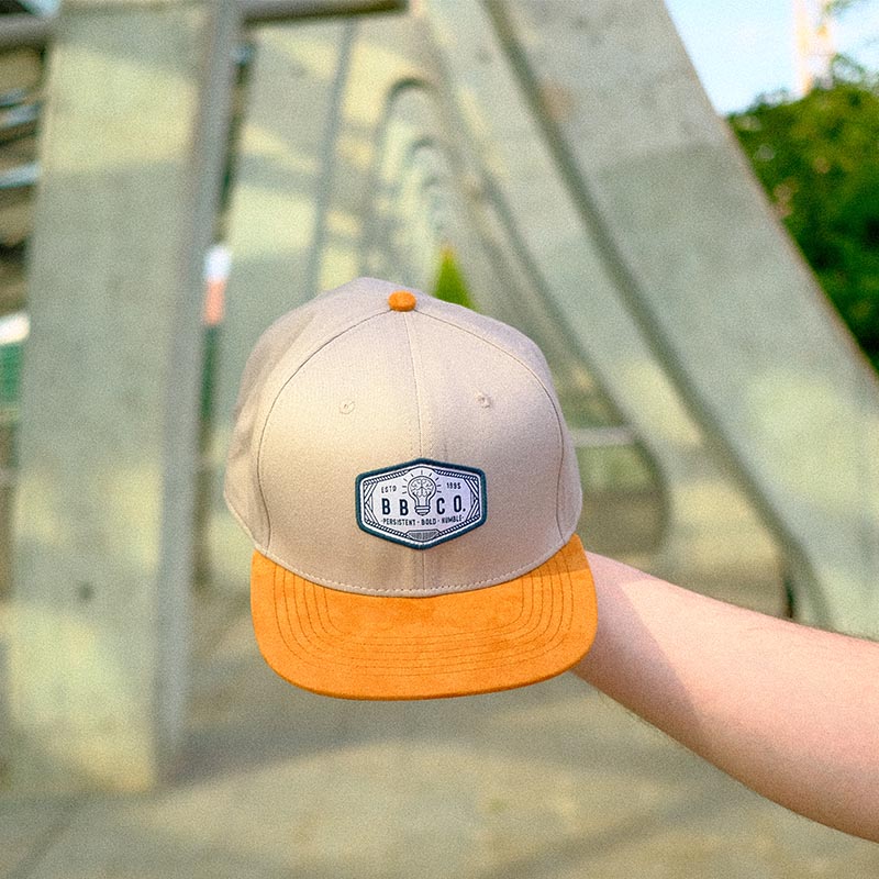 XXL Snapback Cap für große Köpfe wird in Nahaufnahme in die Kamera gehalten.