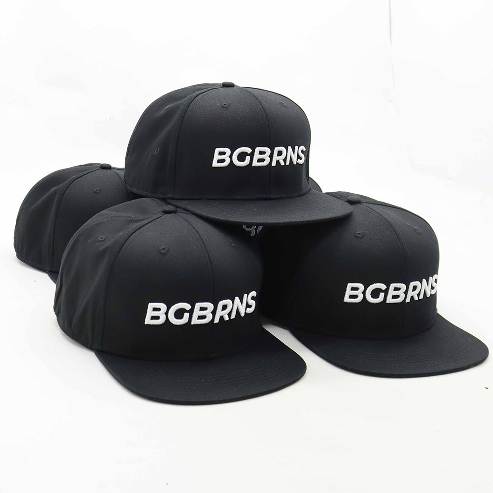 Mehrere BigBrains Snapback Caps für große Köpfe liegen auf einem Tisch. Die Caps sind diagonal nach vorne rechts ausgerichtet.